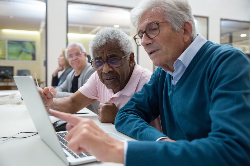 2 older men behind laptop